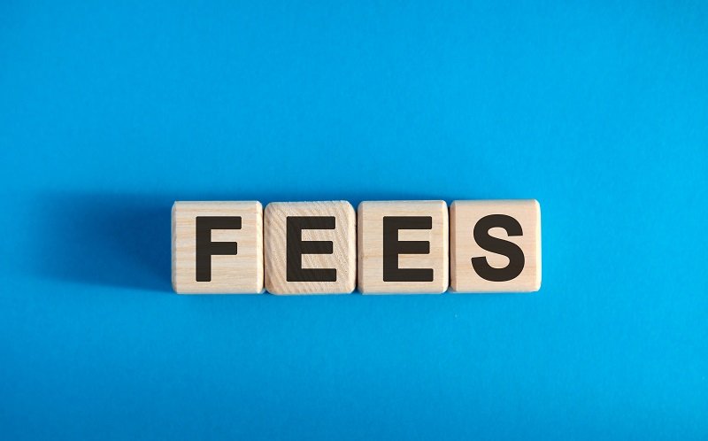 Four wooden blocks on a blue background showing the word Fees.