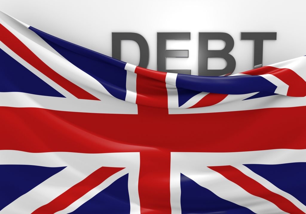 The Union Jack flag folded down at the top right exposing the word DEBT behind it. Government borrowing is at record peacetime levels.